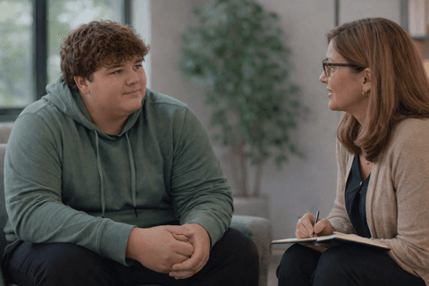 A teen speaking with a professional in a calm consultation setting.
